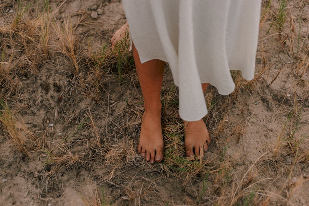 Core values for integrative therapy. Embodied Vitality. Bare feet standing on earth and dry grass, representing sustainable, body-centered healing and nervous system regulation at Lumara Integrative Health.